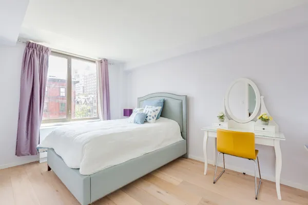 a bedroom with a bed a dresser with wooden floor