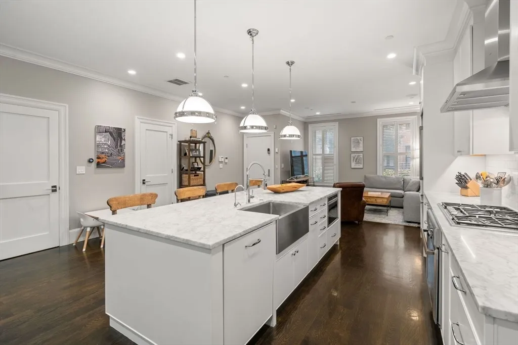a large white kitchen with a large island oven a stove and a wooden floors