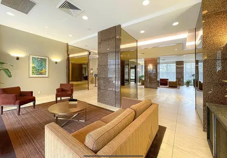 a living room with couches a coffee table and kitchen view with wooden floor