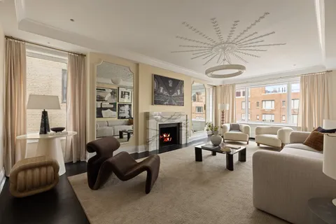 a living room with furniture a fireplace and a floor to ceiling window