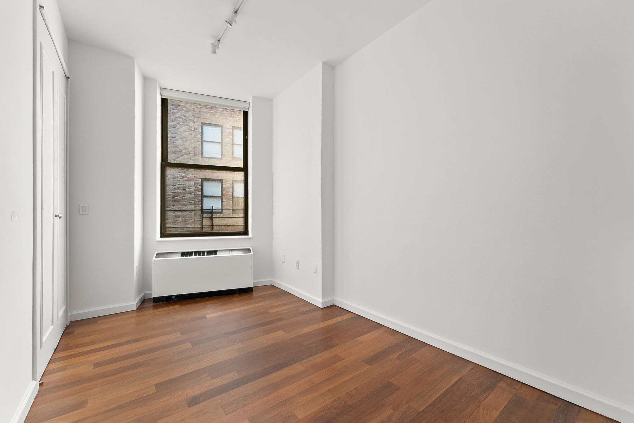 1 Wall Street Court, Unit 1405 Manhattan, NY 10005 - Photo 12 of 19 a view of empty room with wooden floor and fan