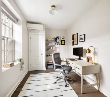 a view of a workspace with furniture and a window