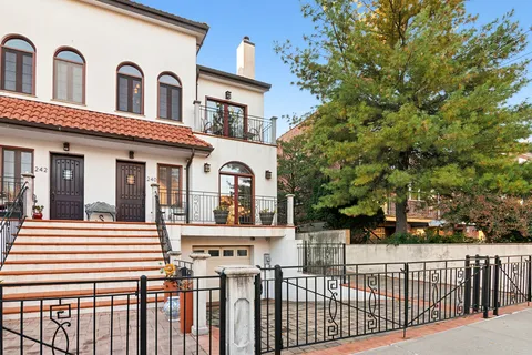 a view of a white house with large windows and a small yard