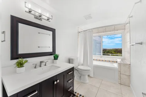a bathroom with a granite countertop sink mirror and a toilet