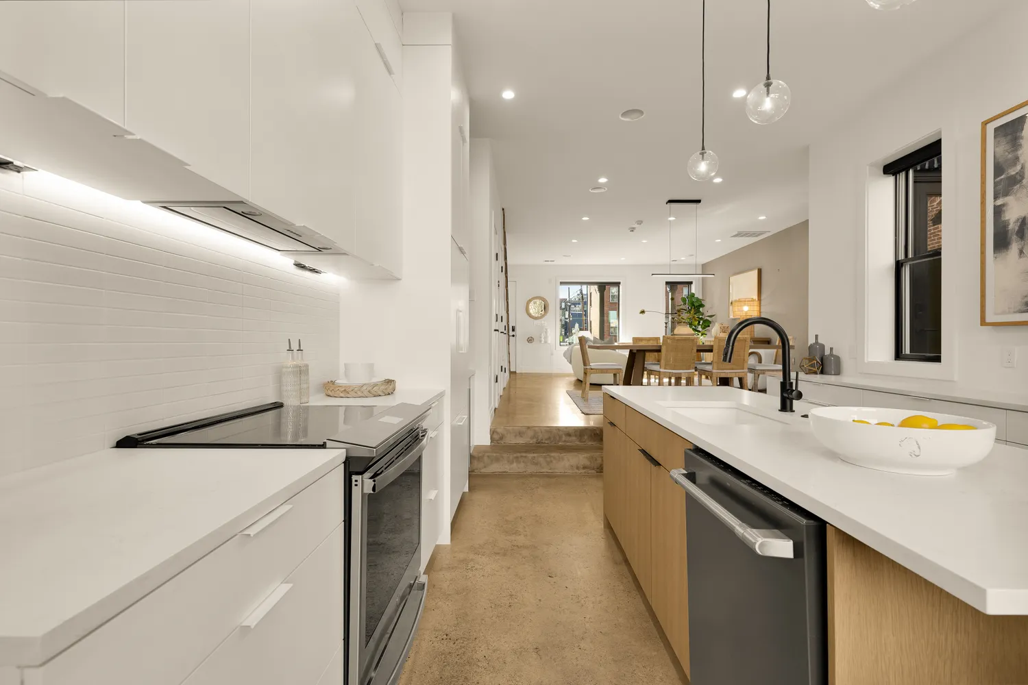 a open kitchen with stainless steel appliances granite countertop a stove a sink a dining table and chairs with wooden floor