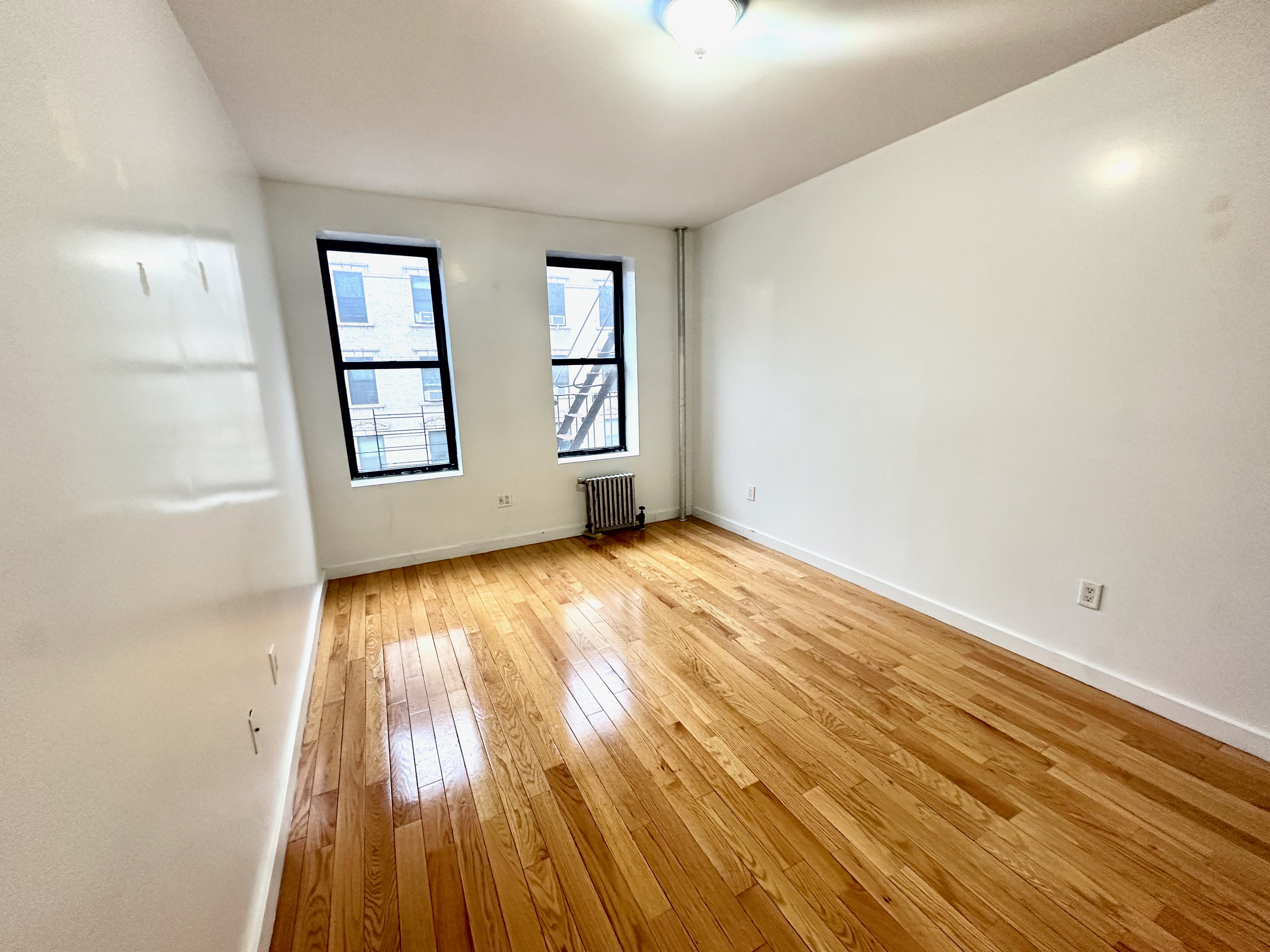 517 West 161st Street, Unit 32 Manhattan, NY 10032 - Photo 3 of 5 an empty room with wooden floor and windows
