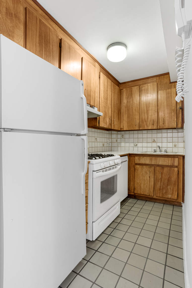 515 East 85th Street, Unit 8C Manhattan, NY 10028 - Photo 9 of 10 a kitchen with a stove a sink and a refrigerator