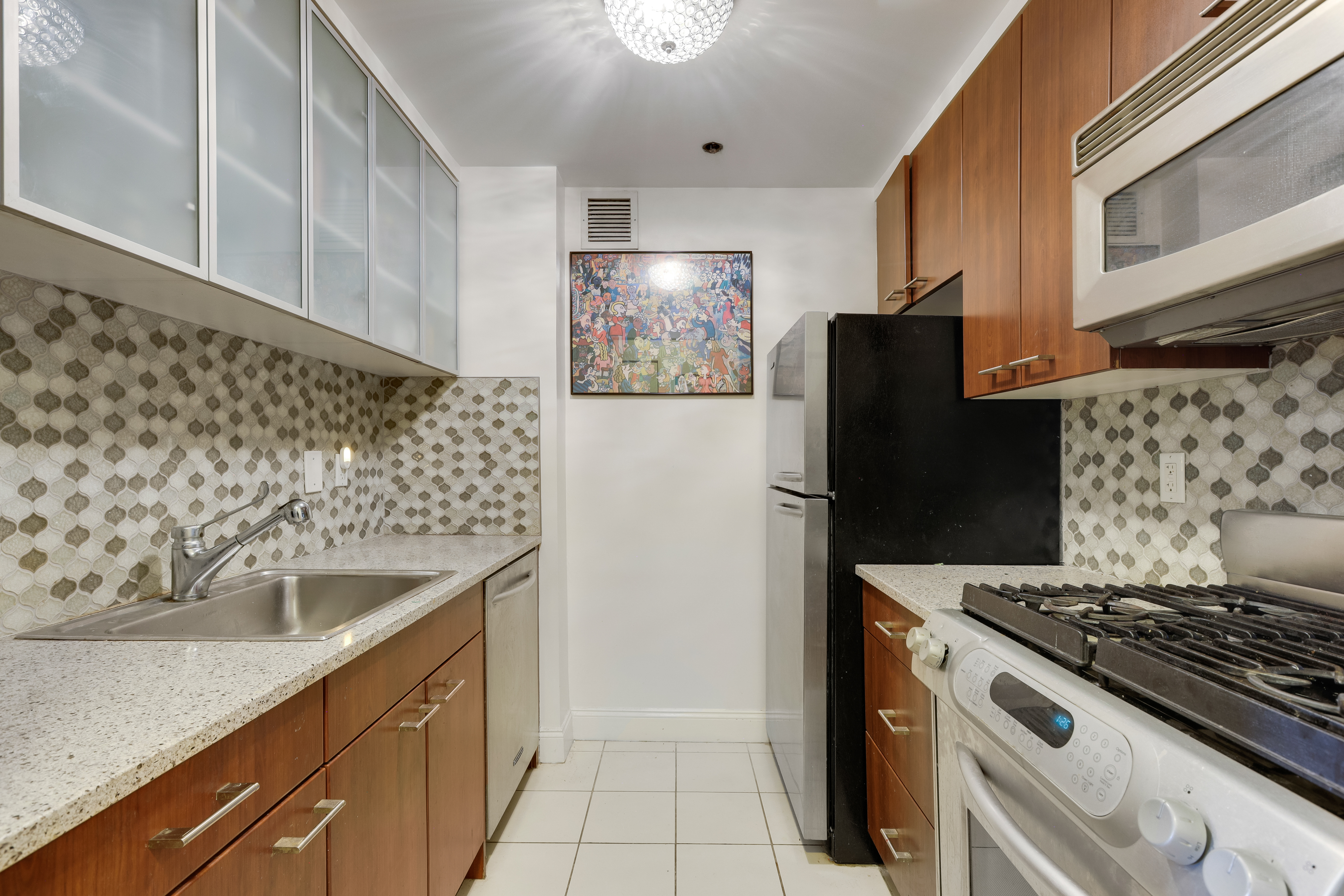215-217 East 96th Street, Unit 25K Manhattan, NY 10128 - Photo 4 of 16 a kitchen with stainless steel appliances granite countertop a refrigerator and a sink