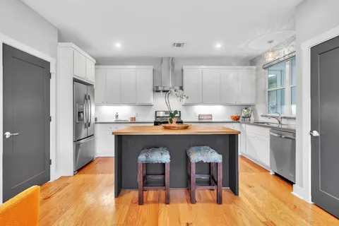 a kitchen with stainless steel appliances granite countertop a dining table chairs refrigerator and sink