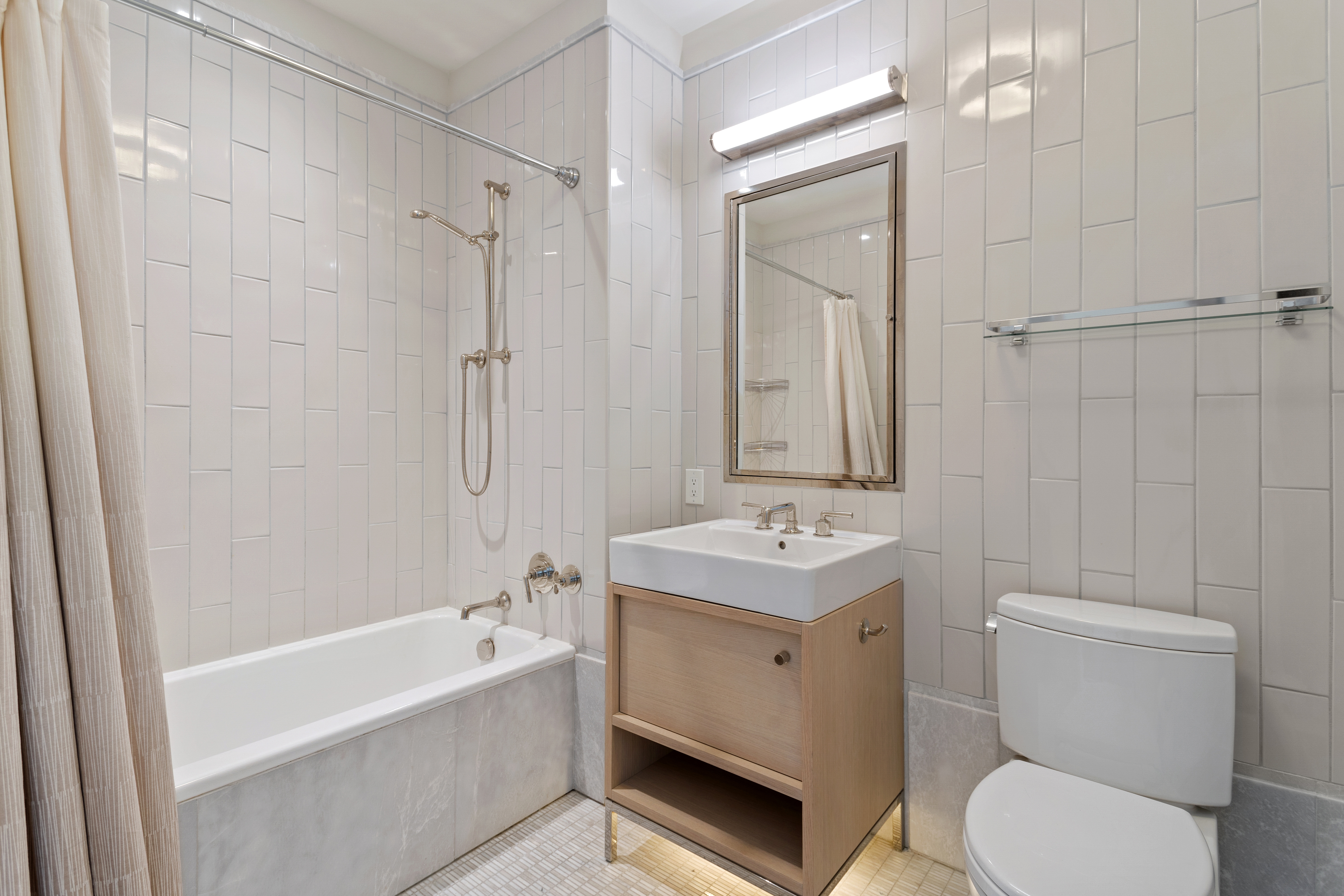 301 East 50th Street, Unit 17B Manhattan, NY 10022 - Photo 4 of 12 a bathroom with a toilet a sink a mirror a bathtub and shower