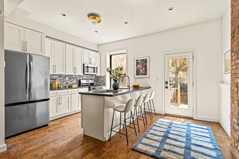 a kitchen with stainless steel appliances granite countertop a refrigerator a stove a sink dishwasher and white cabinets with wooden floor