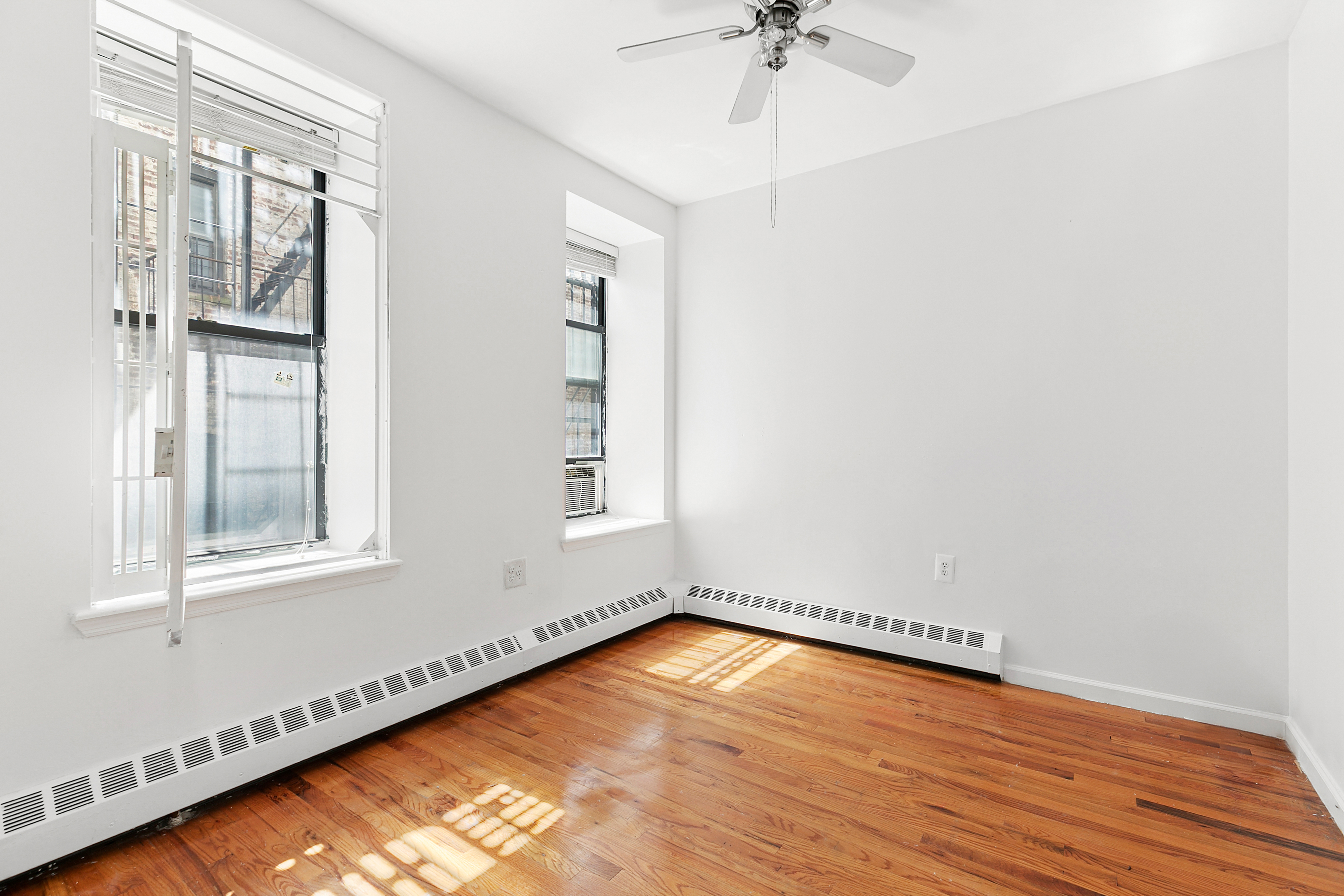 418 West 129th Street, Unit 4 Manhattan, NY 10027 - Photo 7 of 15 a view of an empty room with a window and wooden floor