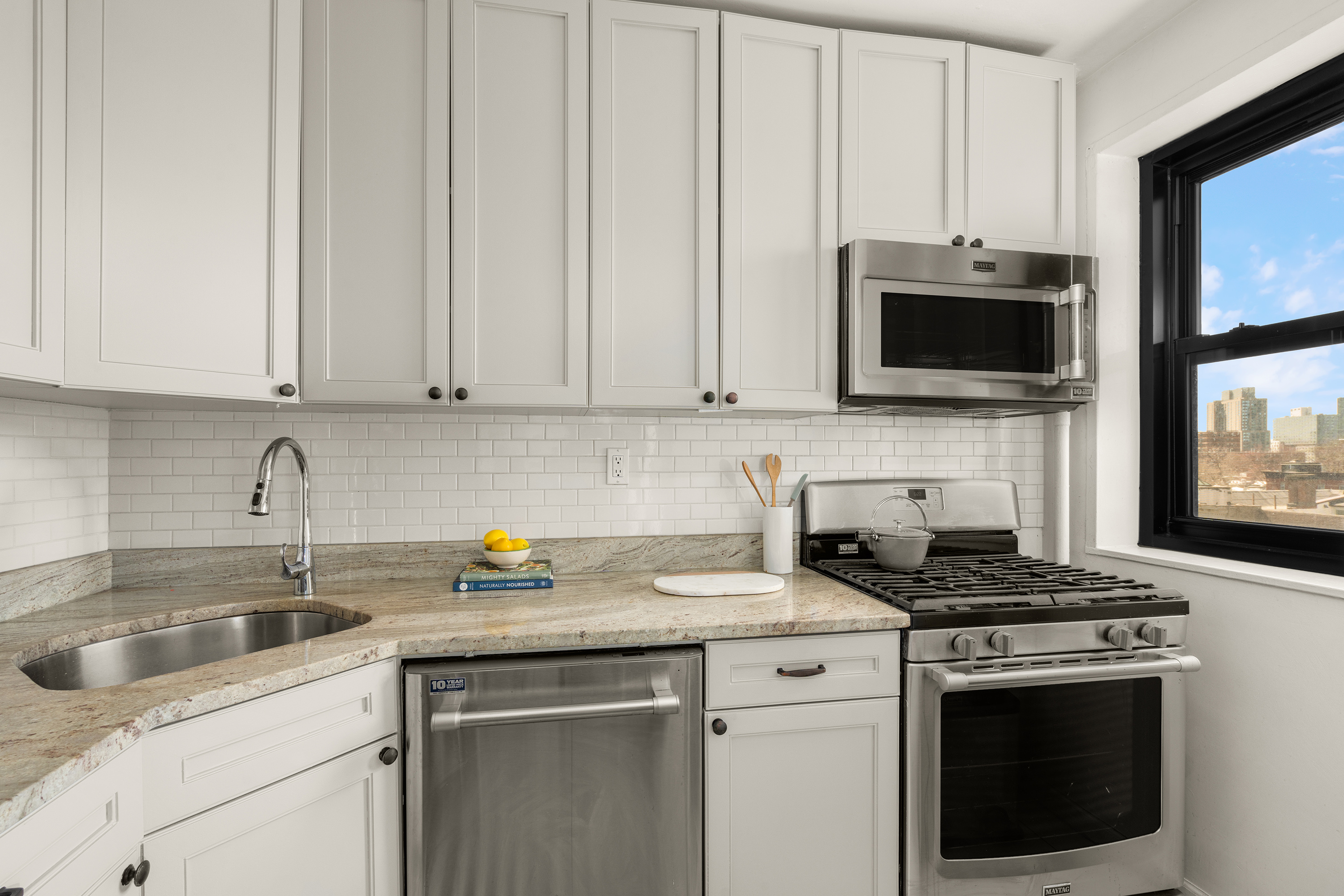 361 Clinton Avenue, Unit 7D Brooklyn, NY 11238 - Photo 3 of 10 a kitchen with granite countertop white cabinets sink and stainless steel appliances
