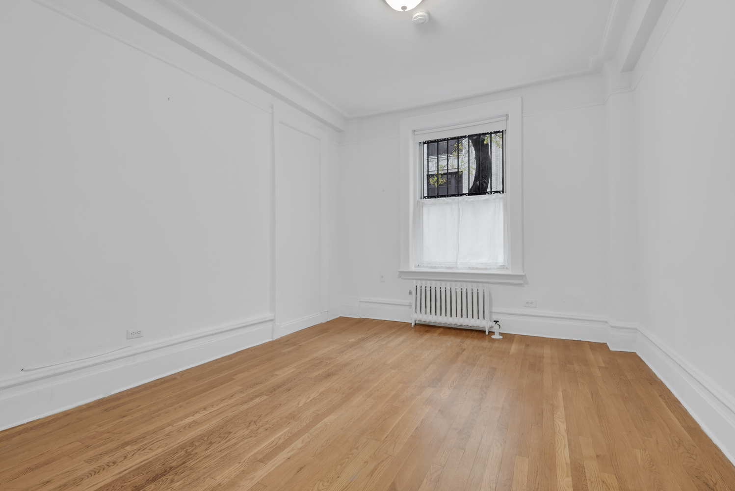 251 West 98th Street, Unit 1B Manhattan, NY 10025 - Photo 4 of 9 an empty room with wooden floor and windows