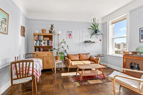 a living room with furniture a bookshelf and a window