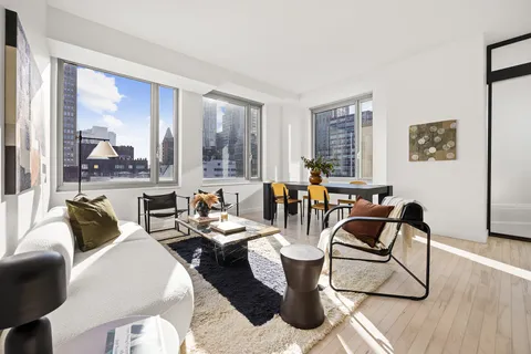 a living room with furniture a large window and wooden floor