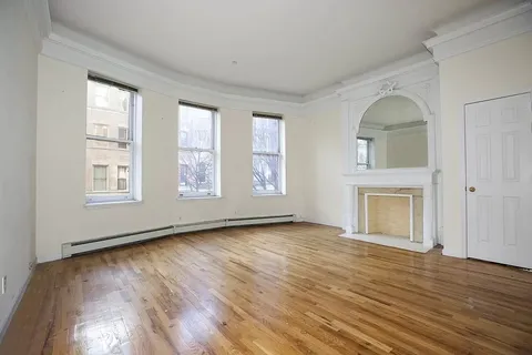 a view of an empty room with window and wooden floor