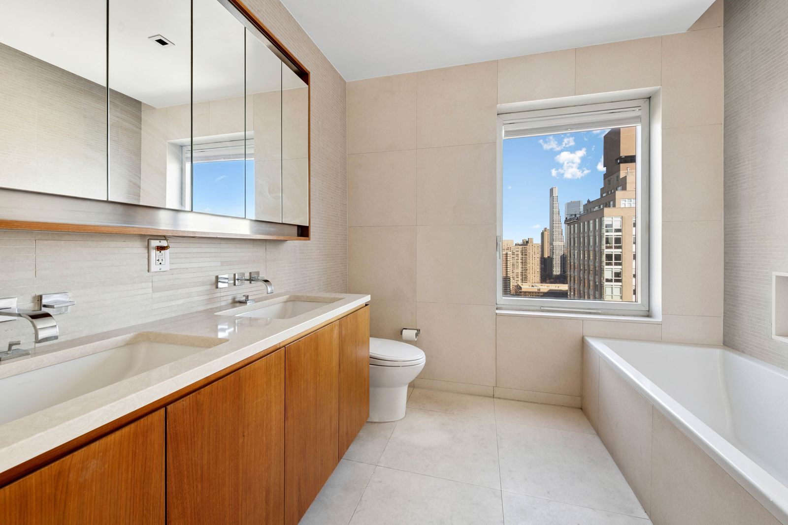 555 West 59th Street, Unit 28D Manhattan, NY 10019 - Photo 6 of 19 a bathroom with a double vanity sink a mirror and a bathtub