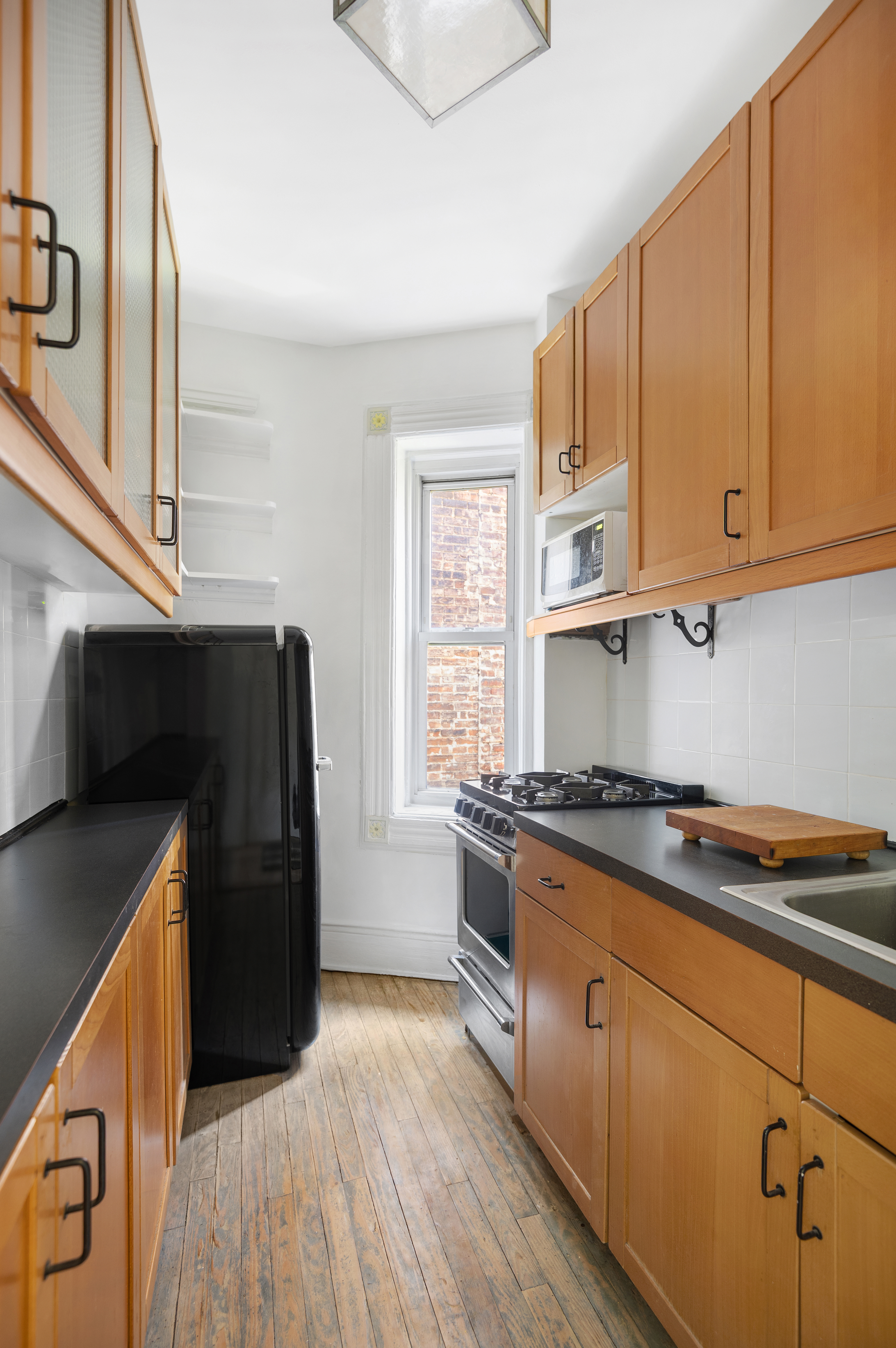 306 West 4th Street, Unit D3 Manhattan, NY 10014 - Photo 3 of 9 a kitchen with granite countertop wooden cabinets and a stove top oven
