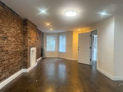 an empty room with wooden floor and brick walls