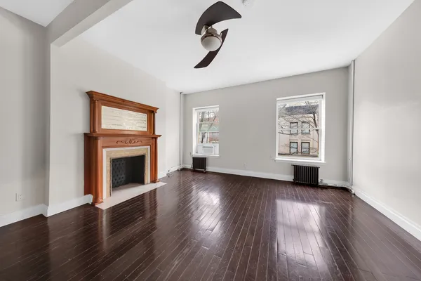 an empty room with windows fireplace and wooden floor