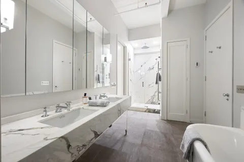 a spacious bathroom with a double vanity sink a mirror and a bathtub
