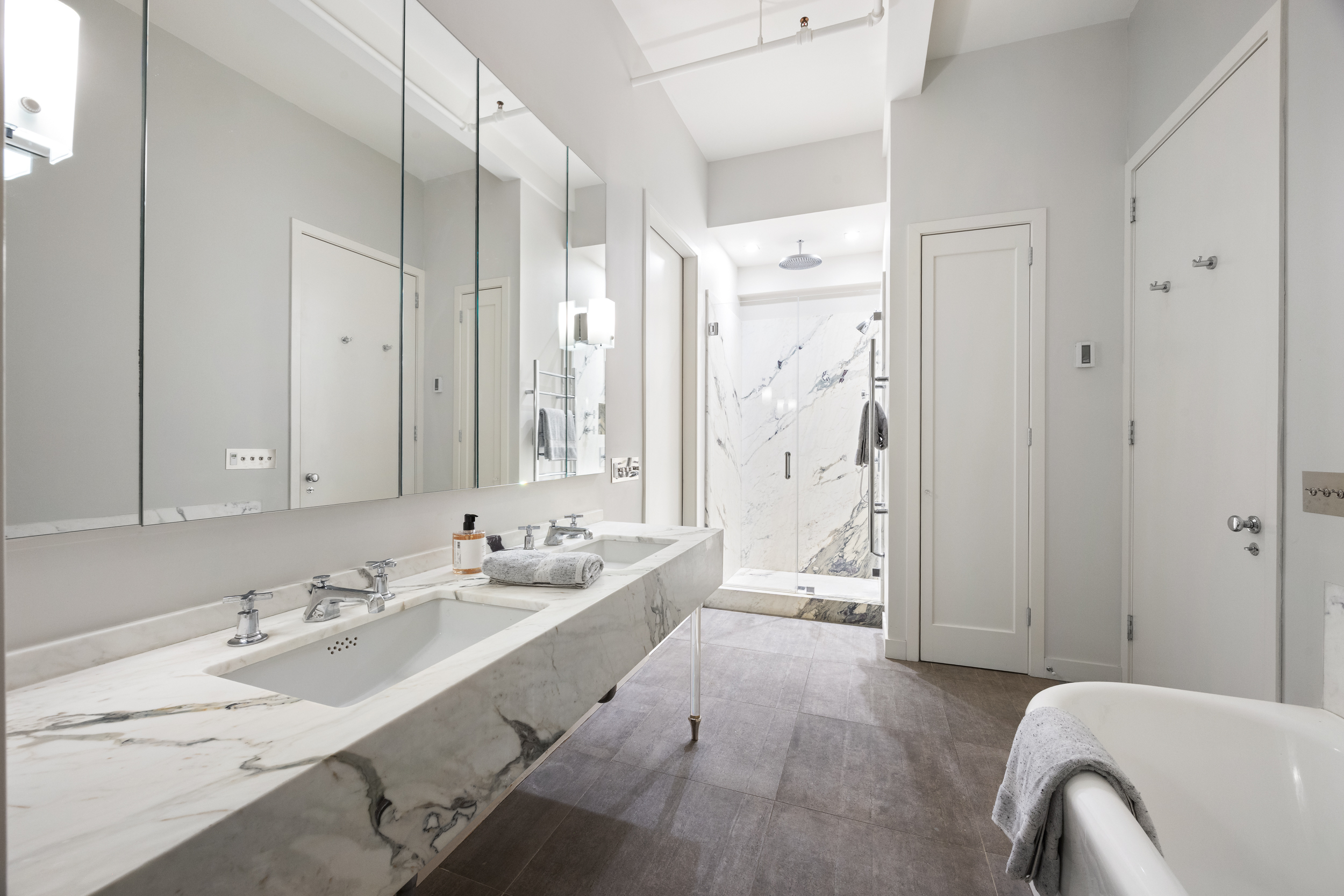 32 West 20th Street, Unit 5 Manhattan, NY 10011 - Photo 12 of 18 a spacious bathroom with a double vanity sink a mirror and a bathtub