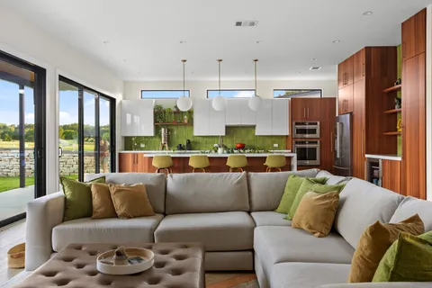 a living room with furniture kitchen view and large windows