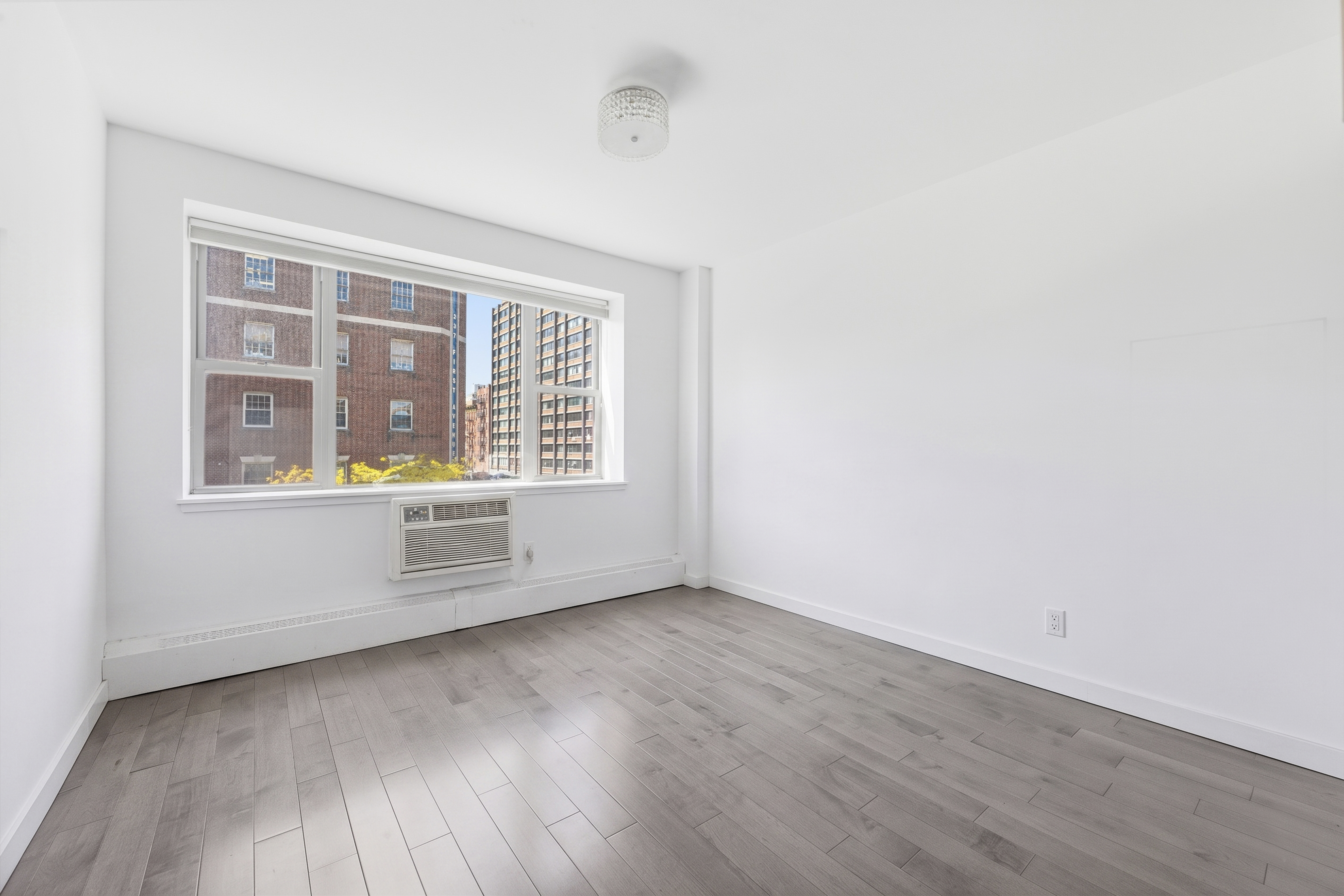 400 East 14th Street, Unit 4C Manhattan, NY 10009 - Photo 4 of 8 an empty room with wooden floor and windows