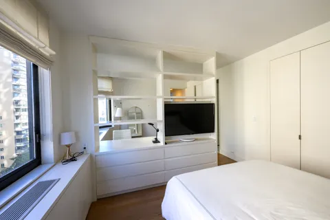 a bedroom with bed and flat tv screen on the dresser