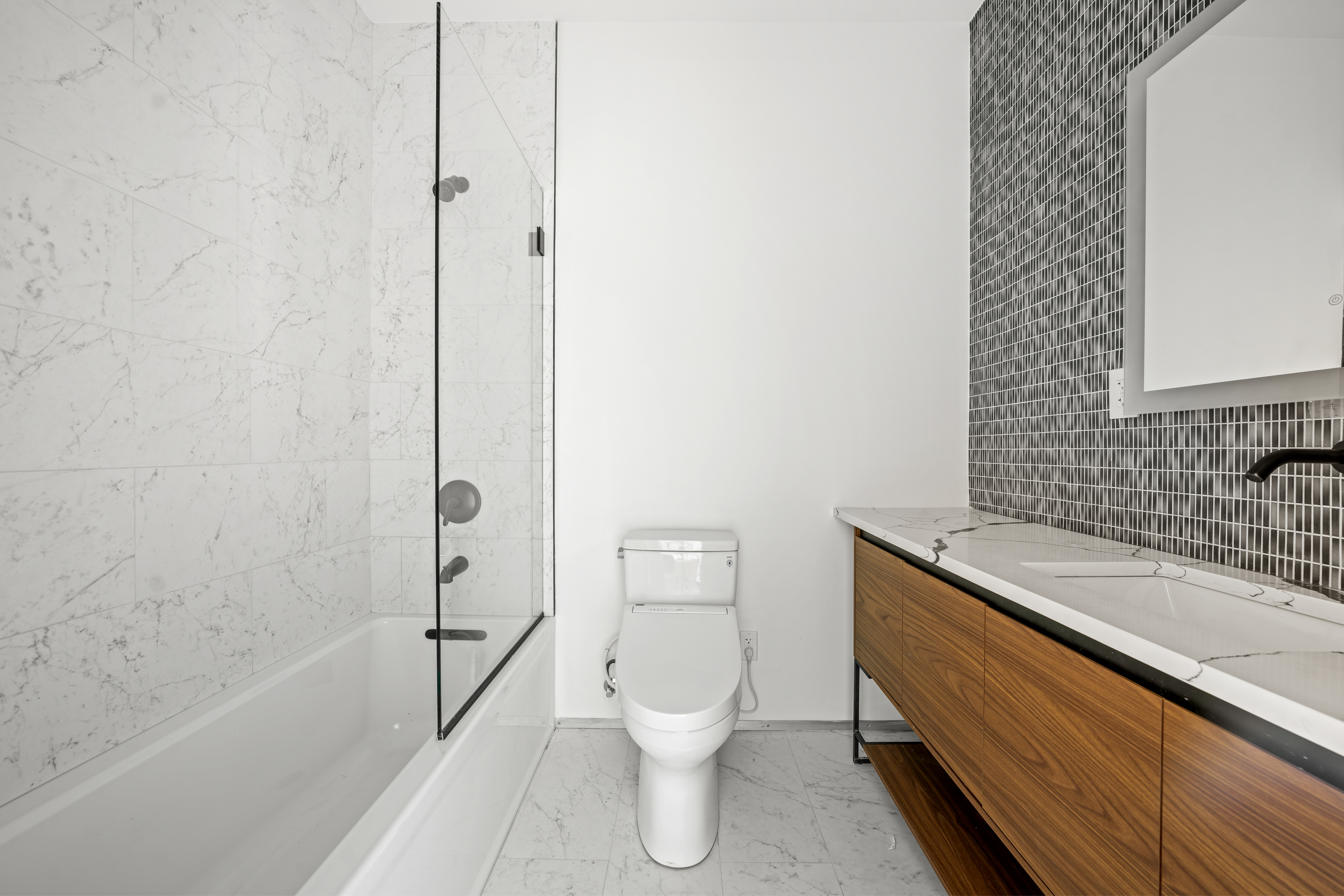 953 St Nicholas Avenue, Unit 1 Manhattan, NY 10032 - Photo 11 of 15 a bathroom with a granite countertop toilet a sink and bathtub