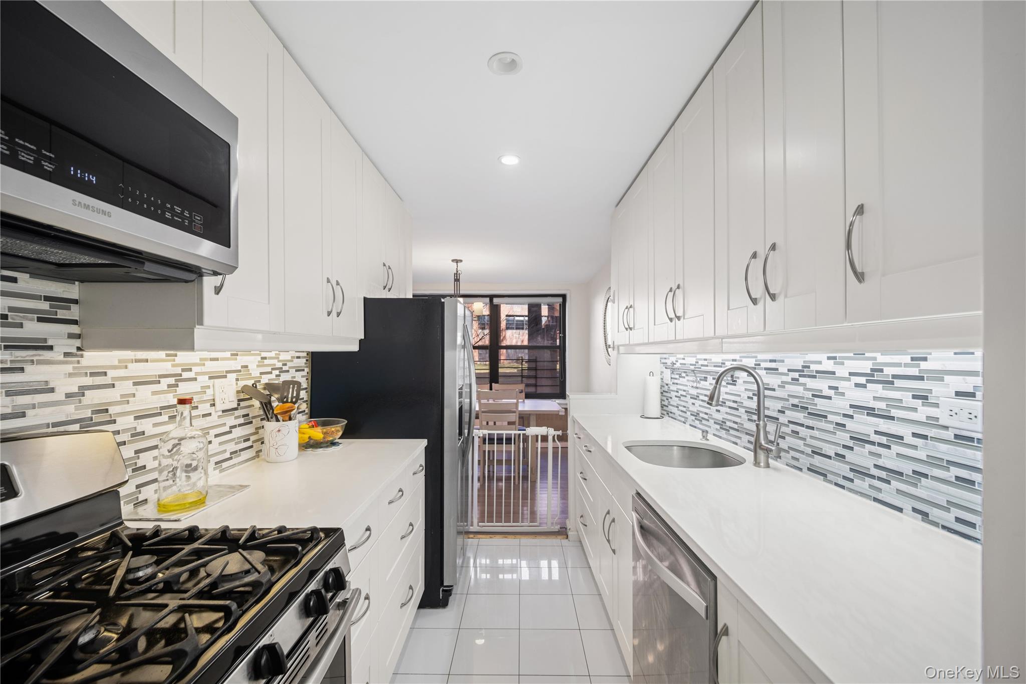 75-34 Bell Boulevard, Unit LD Queens, NY 11364 - Photo 5 of 26 a kitchen with stainless steel appliances a sink stove top oven and cabinets