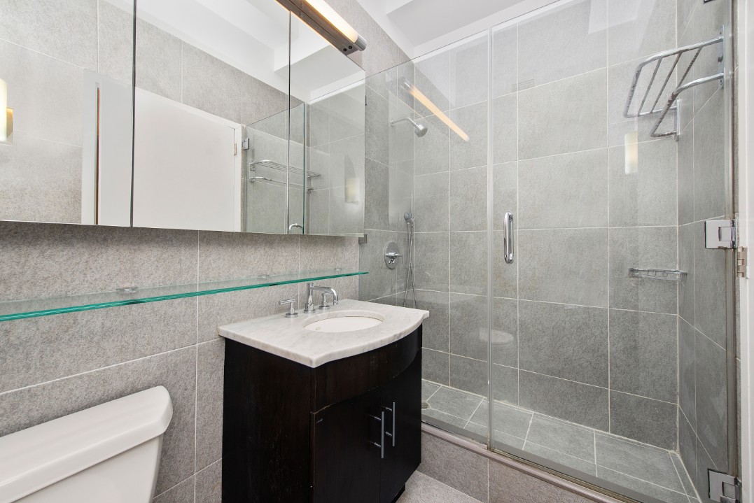 80 John Street, Unit 4C Manhattan, NY 10038 - Photo 6 of 11 a bathroom with a sink toilet vanity and shower