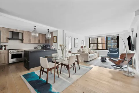 a living room with furniture a rug kitchen view and a large window