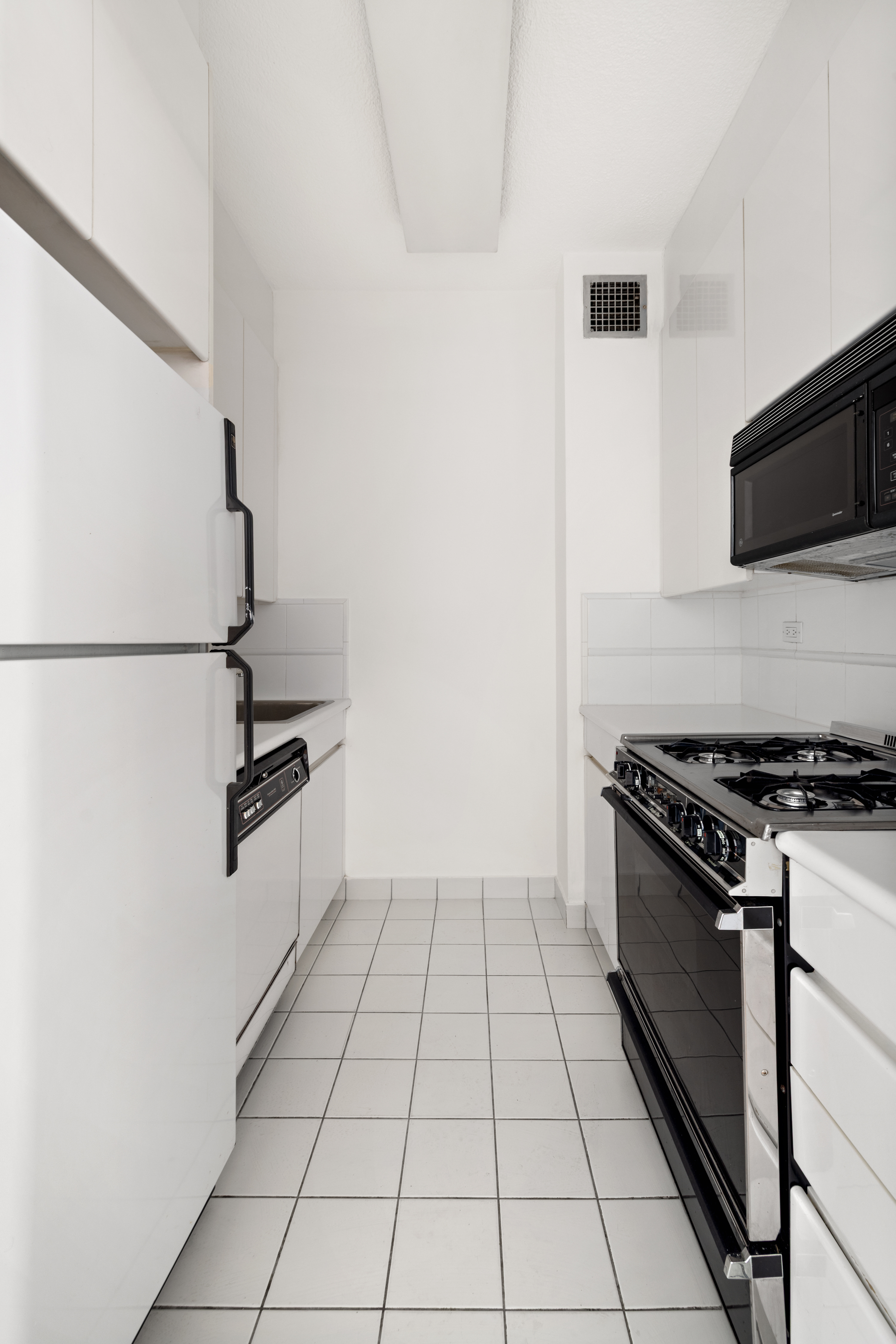 60 East 8th Street, Unit 15D Manhattan, NY 10003 - Photo 5 of 14 a kitchen with granite countertop a stove and a refrigerator