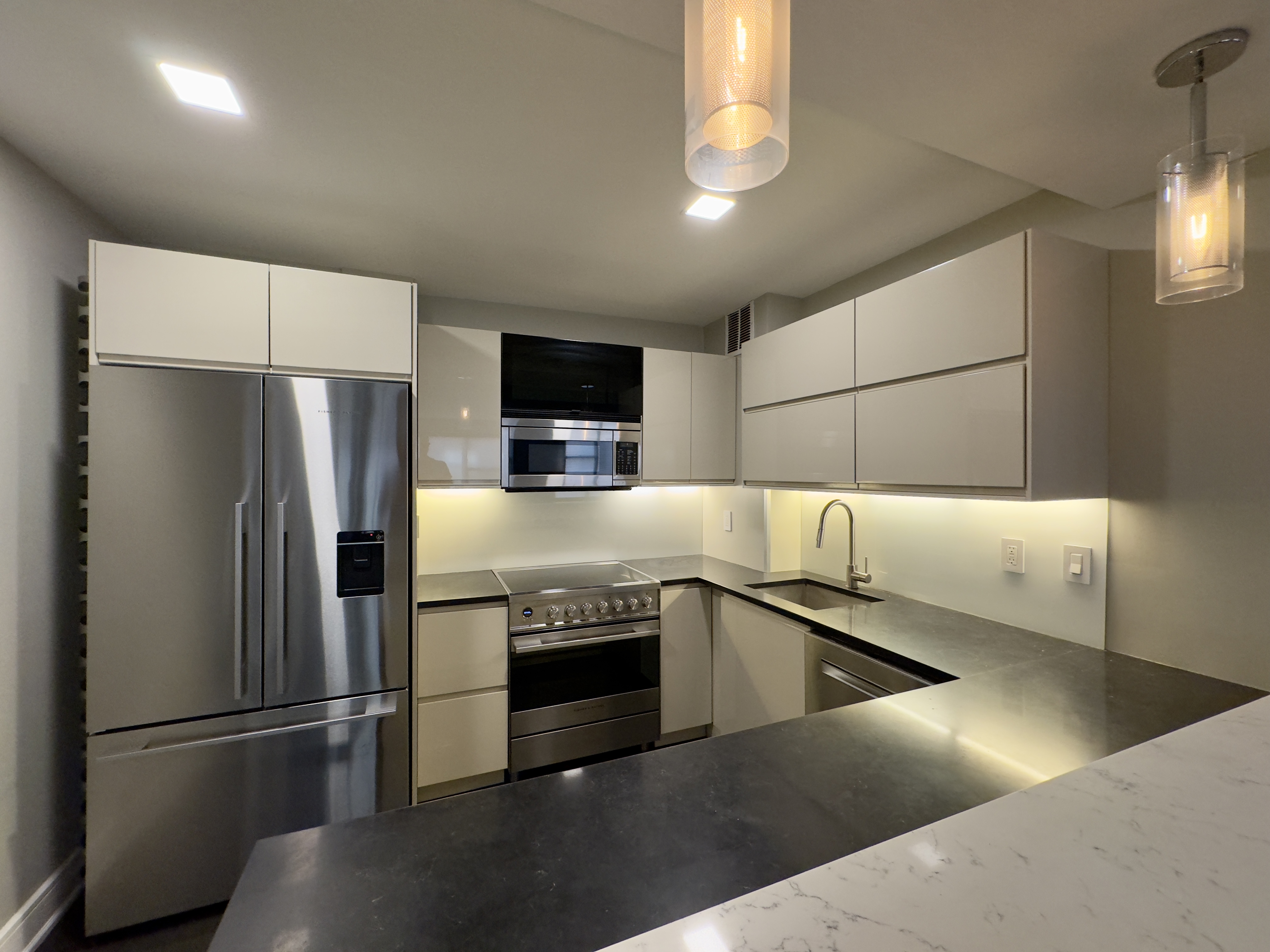 2 Tudor City Place, Unit 12DS Manhattan, NY 10017 - Photo 10 of 20 a kitchen with stainless steel appliances granite countertop a refrigerator a stove and a sink with wooden floor