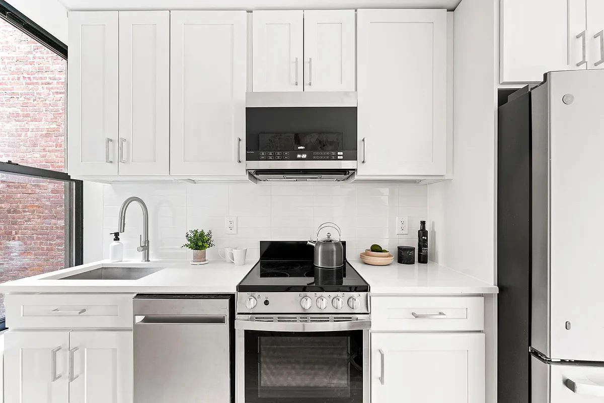 168 Sumpter Street, Unit 2 Brooklyn, NY 11233 - Photo 3 of 10 a kitchen with stainless steel appliances granite countertop white cabinets a stove a microwave and a refrigerator