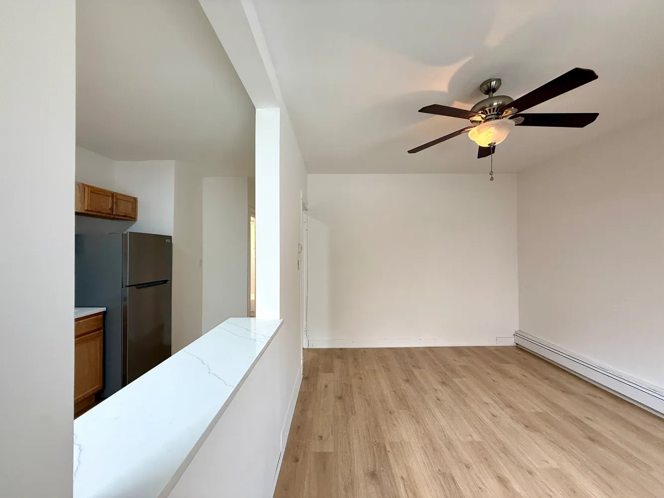 a view of a hallway with wooden floor and a ceiling fan