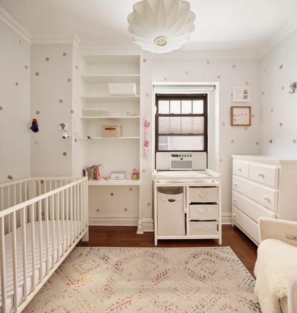 a room with a baby bed baby crib and a window