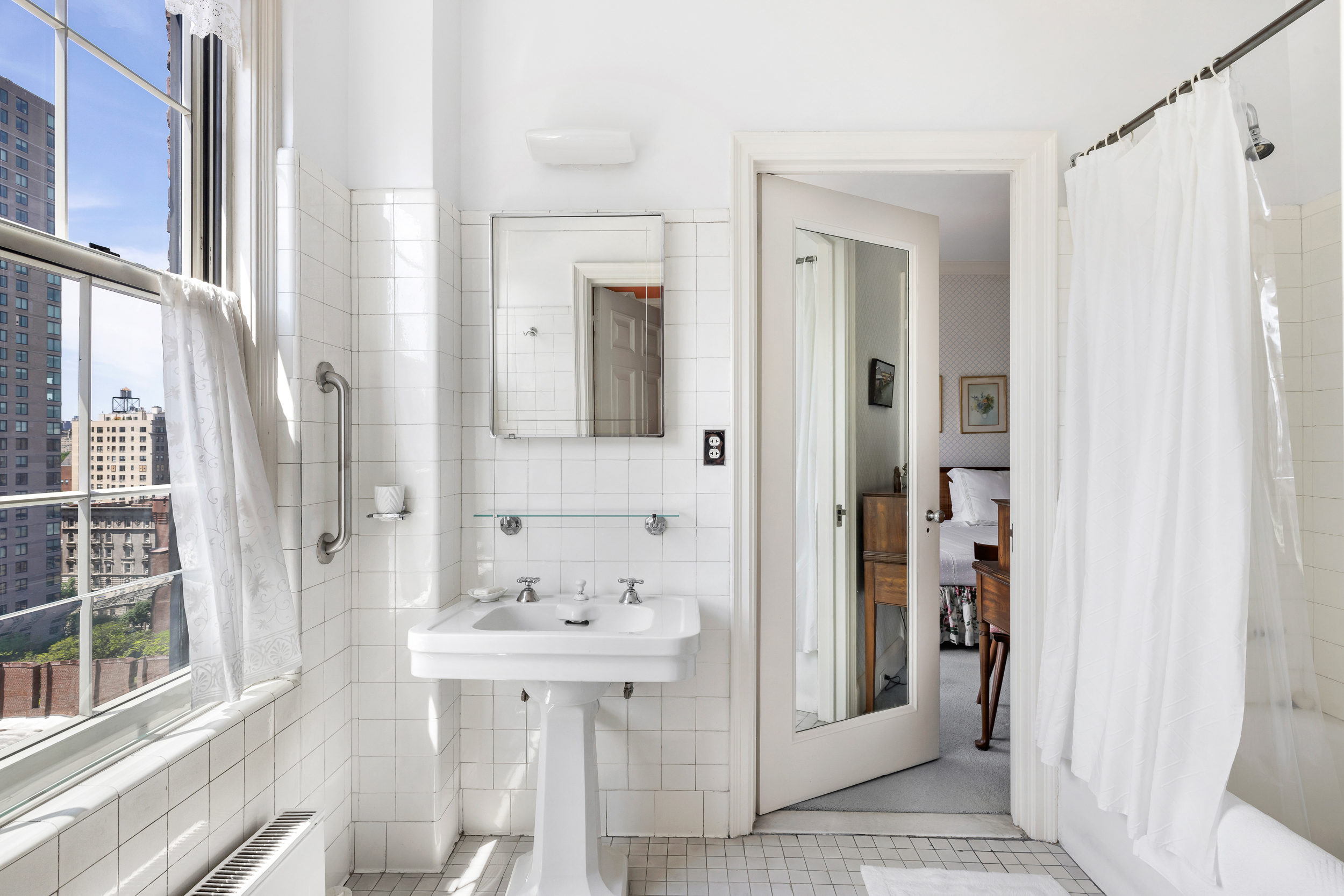 1220 Park Avenue, Unit 12B Manhattan, NY 10128 - Photo 11 of 12 a bathroom with a sink a mirror and a shower