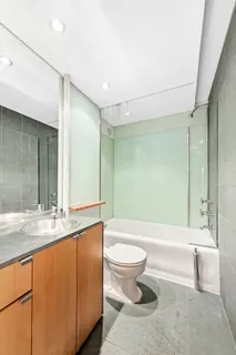 a bathroom with a granite countertop sink toilet mirror and bathtub
