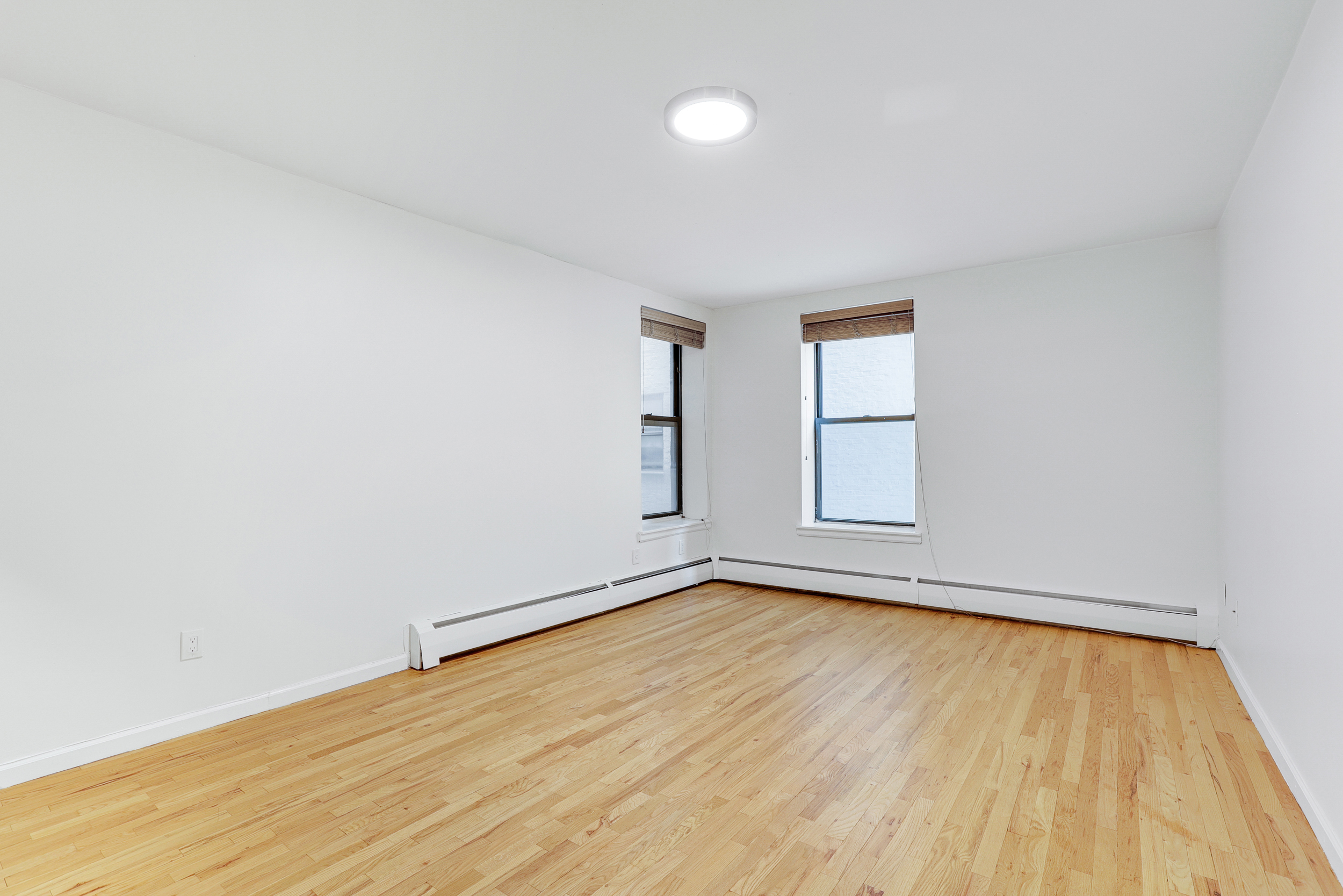 66-72 St Nicholas Avenue, Unit 3G Manhattan, NY 10026 - Photo 4 of 15 an empty room with wooden floor and windows