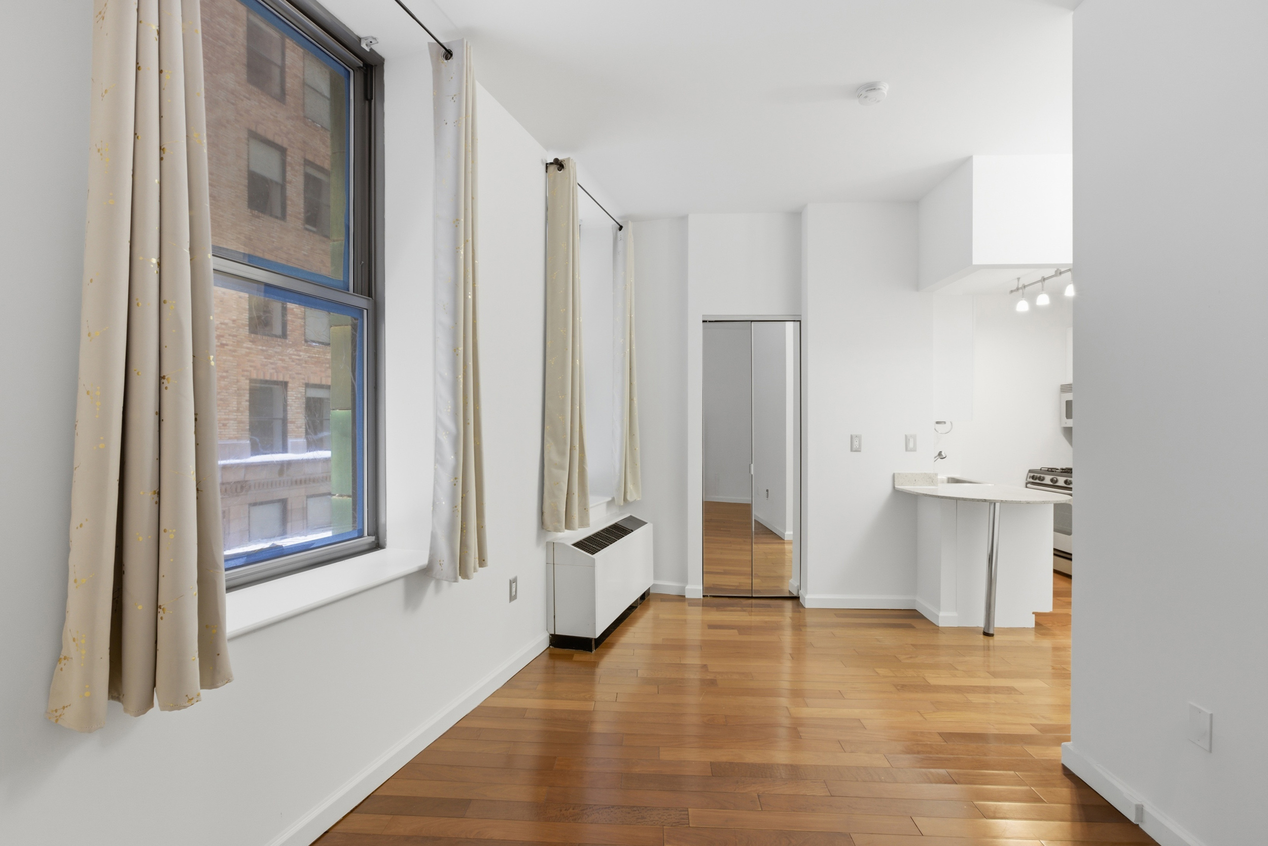 1 Wall Street Court, Unit 406 Manhattan, NY 10005 - Photo 1 of 7 a view of an empty room with cabinet and a window