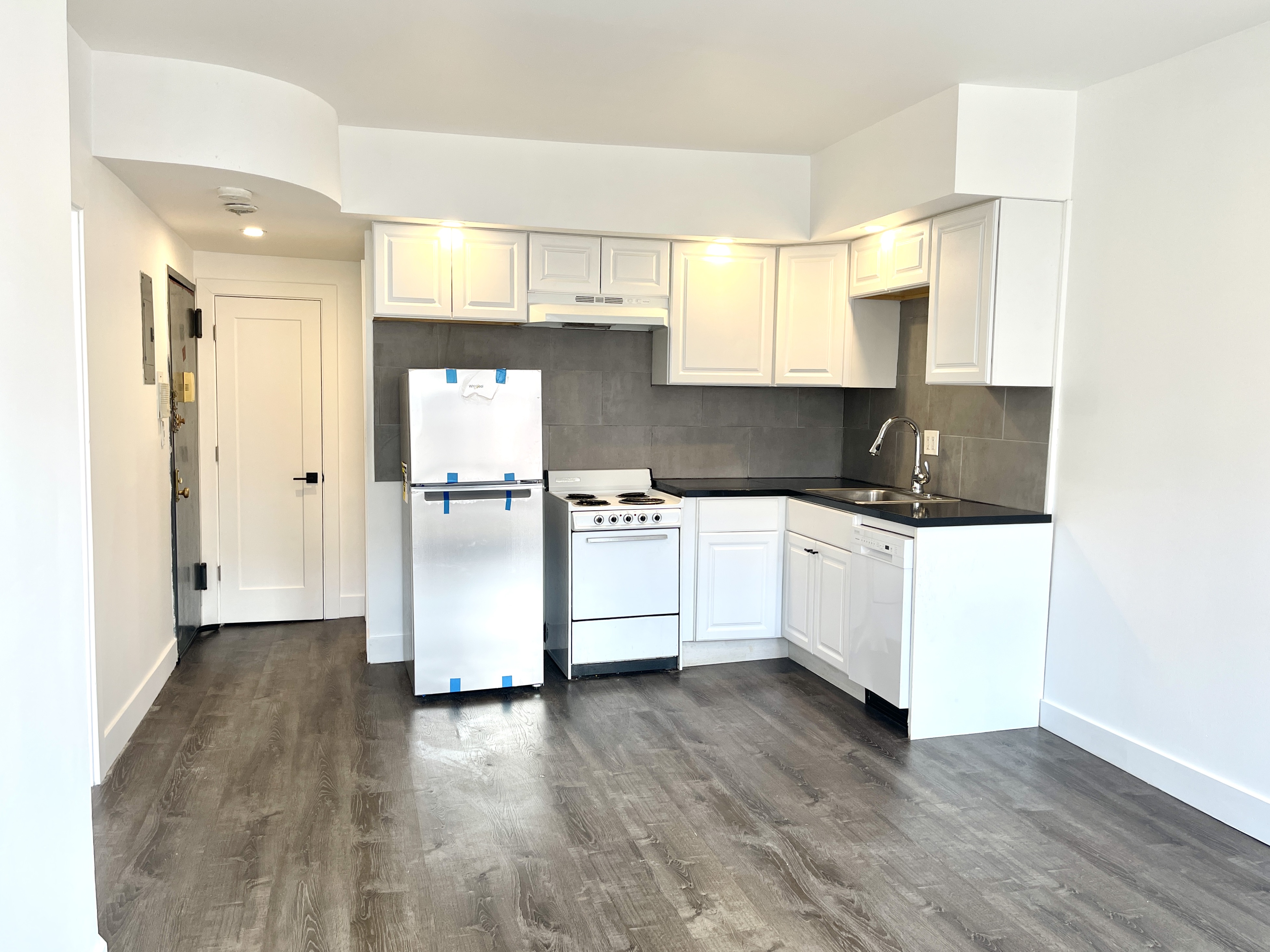 a kitchen with stainless steel appliances white cabinets and wooden floor