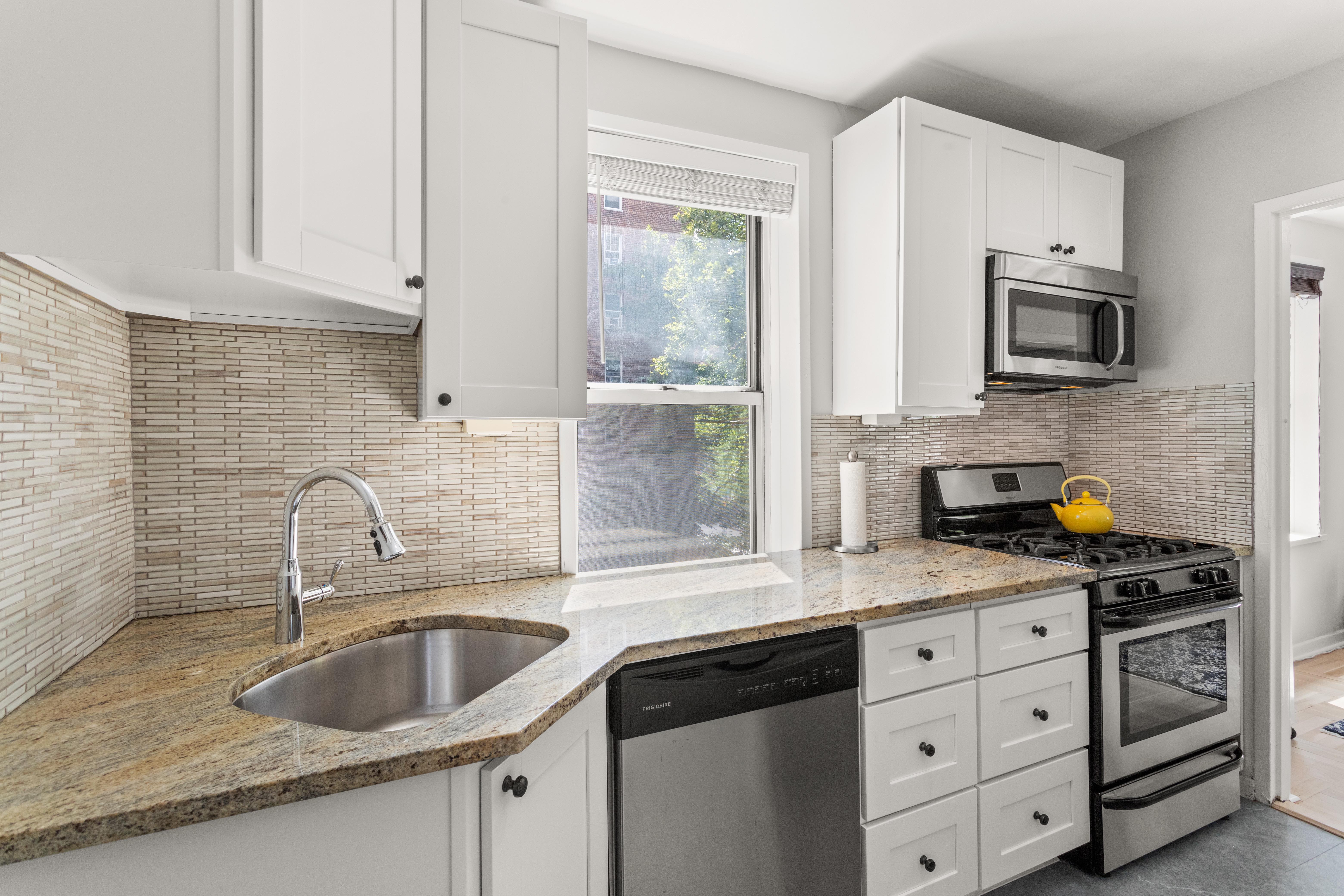 66 Overlook Terrace, Unit 4K Manhattan, NY 10040 - Photo 9 of 26 a kitchen with granite countertop a sink white cabinets and window