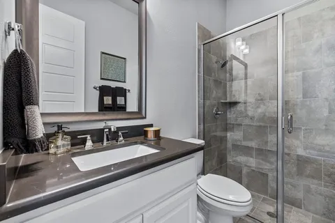 a bathroom with a sink a toilet a mirror and shower
