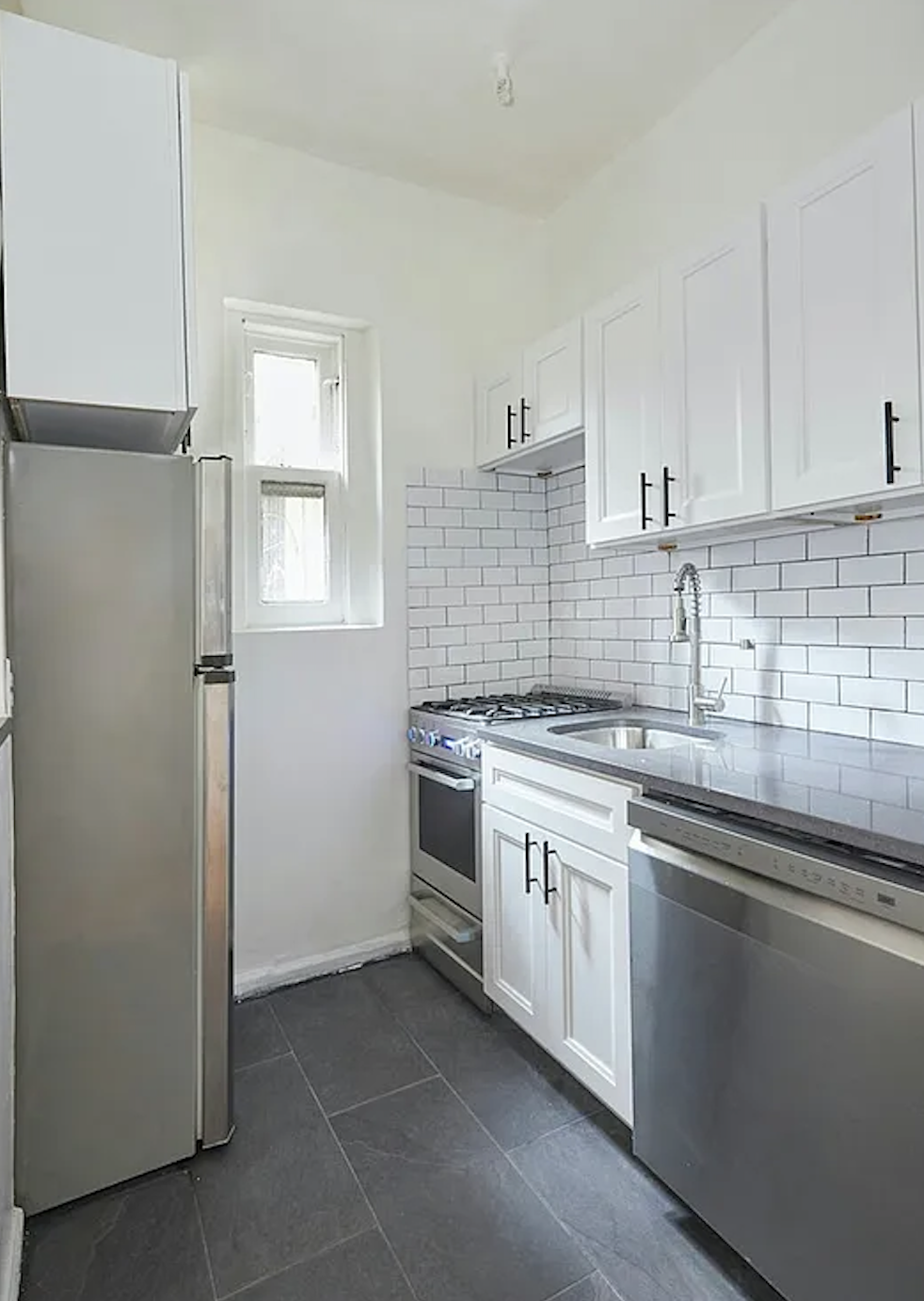 405 East 82nd Street, Unit 1B Manhattan, NY 10028 - Photo 5 of 10 a kitchen with stainless steel appliances granite countertop a sink and a refrigerator