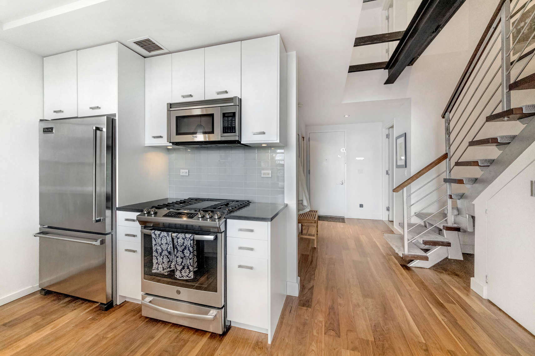 2-17 51st Avenue, Unit 606 Queens, NY 11101 - Photo 4 of 18 a kitchen with stainless steel appliances granite countertop a stove a refrigerator and a microwave