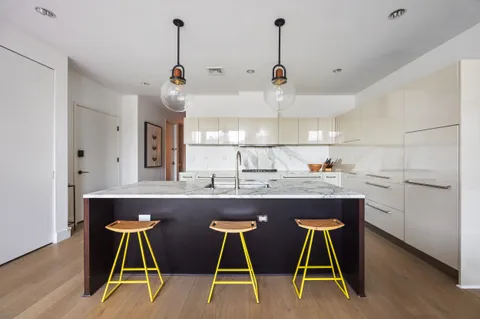 a kitchen with kitchen island stainless steel appliances a dining table chairs sink and cabinets