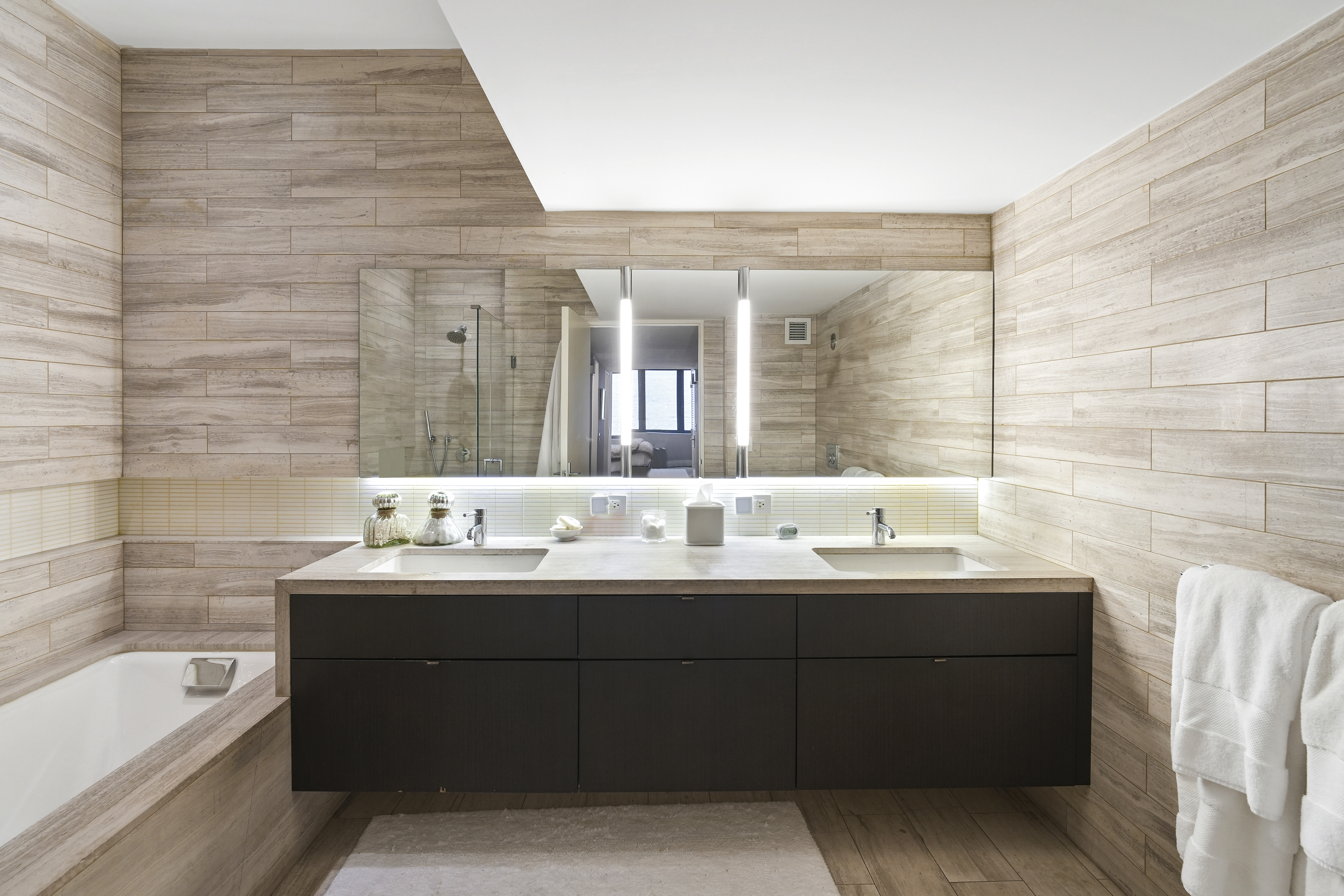 421 Hudson Street, Unit 221 Manhattan, NY 10014 - Photo 12 of 21 a bathroom with a double vanity sink and mirror with bathtub